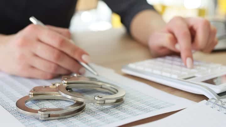 Interpol Leverages Global System to Curtail Fraud Payments 3 accountant with handcuffs megaflopp shutterstock i6Rlpr